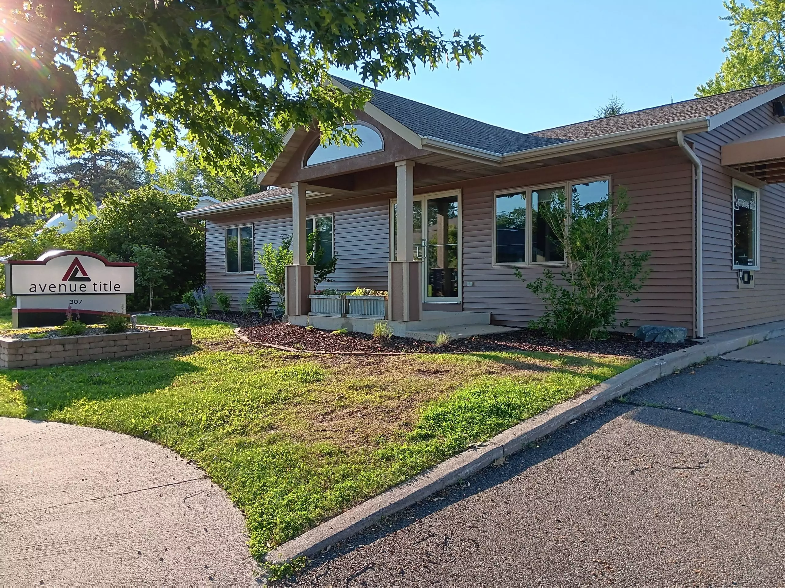 Avenue Title office building exterior with sign, front entrance, and landscaped lawn